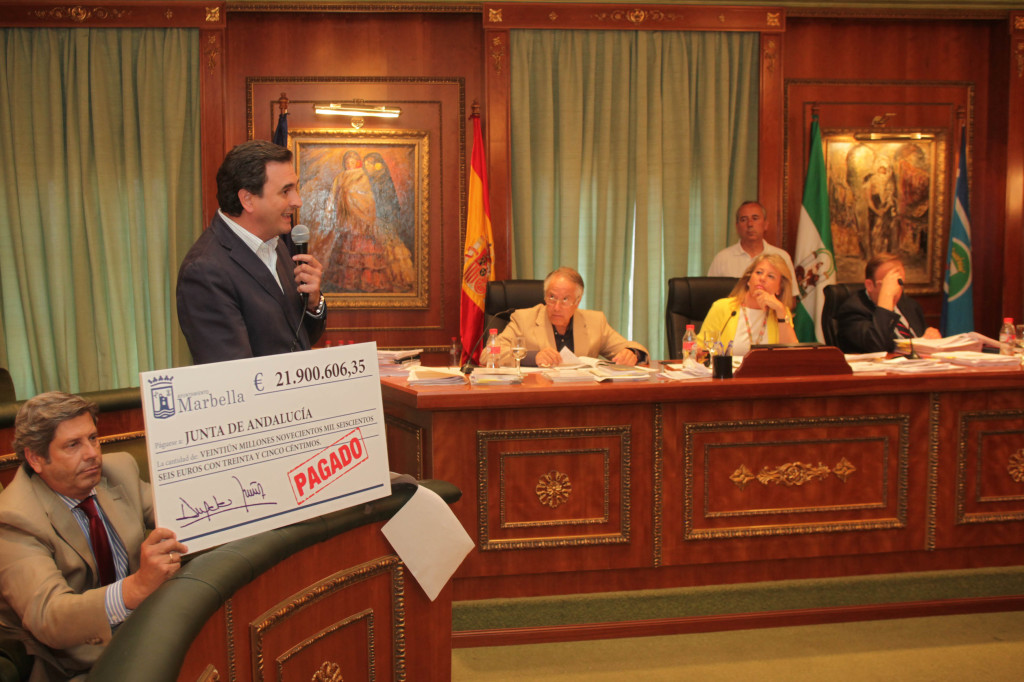 El concejal de Urbanismo, Pablo Moro, sostiene un cheque gigante, durante la intervención del portavoz del PP, Félix Romero