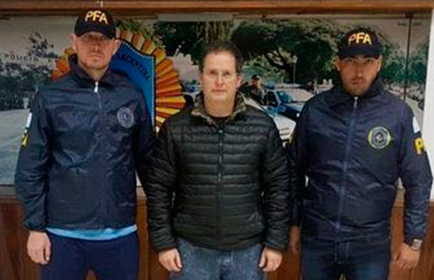 Carlos Fernández custodiado por dos agentes de la Policía Federal Argentina tras su detención. FOTO/ Policía Federal Argentina
