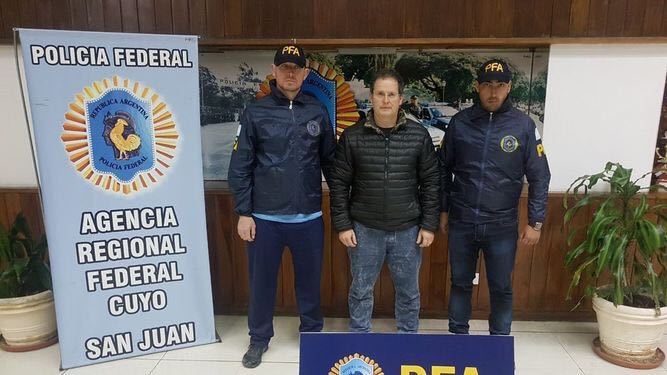 Carlos Fernández custodiado por dos agentes de la Policía Federal Argentina tras su detención. FOTO/ Policía Federal Argentina