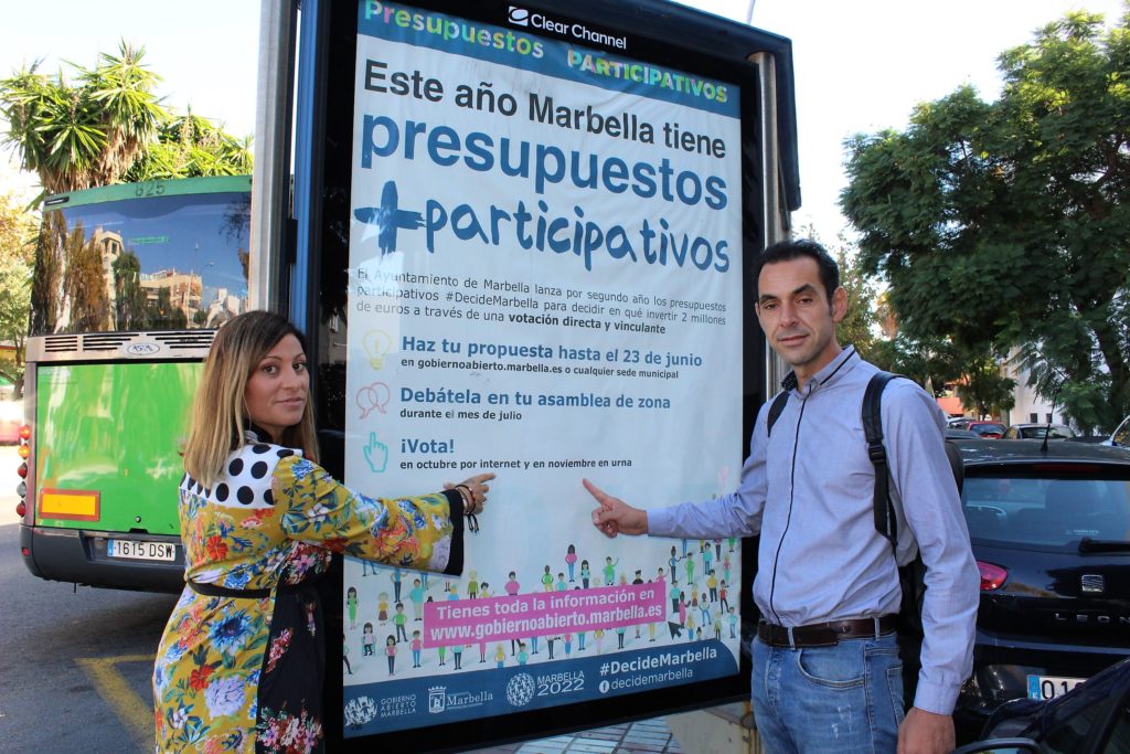 Los concejales de Izquierda Unida de Marbella Miguel Díaz y Victoria Morales señalan un cartel de su iniciativa 'Presupuestos Participativos', creada cuando gobernaron entre 2015 y 2017. FOTO/ IU