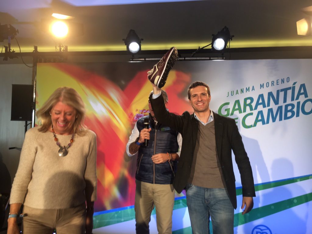 El presidente del PP, Pablo Casado, muestra las zapatillas deportivas que le ha regalado el jefe de campaña del PP-A, Elías Bendodo, en presencia de la alcaldesa de Marbella, Ángeles Muñoz, este jueves durante una acto celebrado en Marbella. FOTO/ CABANILLAS