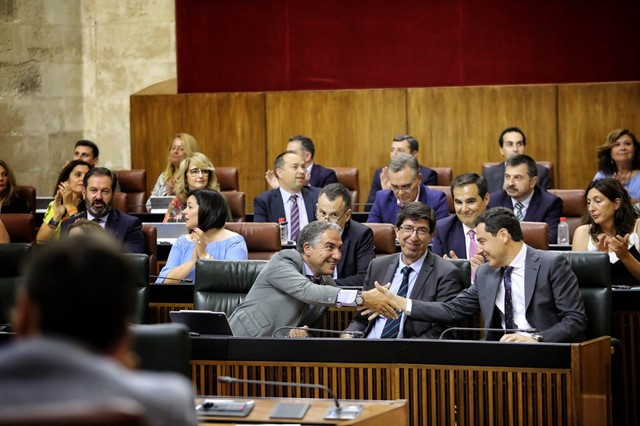 El consejero de Presidencia de la Junta, Elías Bendodo y el presidente, Juanma Moreno, se saludan en presencia del vicepresidente, Juan Marín, durante la votación de este miércoles en el Parlamento Andaluz. FOTO/ Junta de Andalucía