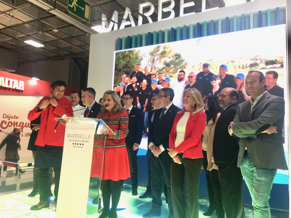 La alcaldesa de Marbella, Ángeles Muñoz (drcha) junto al presidente de la Diputación, Francisco Salado, y una representación de los cocineros que han participado en esta primera jornada del stand de Fitur, con María Asenjo (Marbella All Stars) en el atril. FOTO CABANILLAS