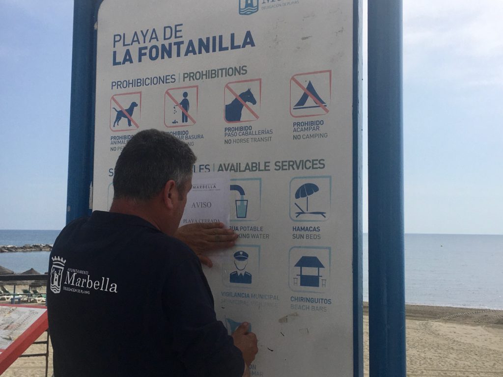 Un operario del Ayuntamiento de Marbella pega un cartel en el que se advierte de la playa cerrada este sábado. FOTO/ CABANILLAS